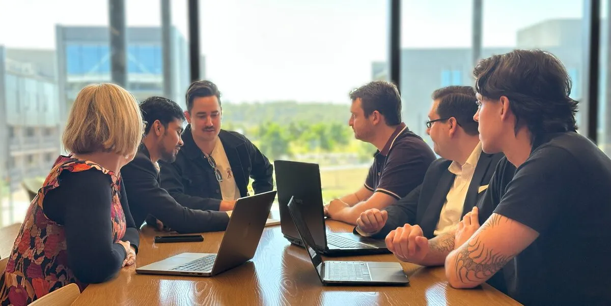 The Cadent team working together around a table of laptops.